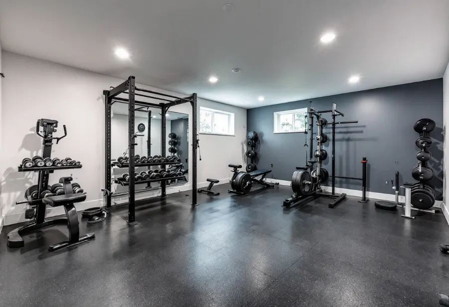 Basement home gym with rubber flooring, racks and weights